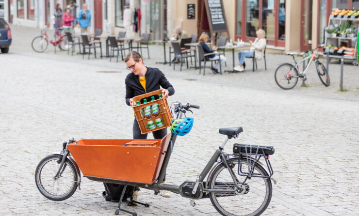 Rund 80.000 km sind Radler*innen bereits mit ihren Lastenrädern gefahren (im Bild: Frau hebt einen Kasten Wasser in das Lastenrad)